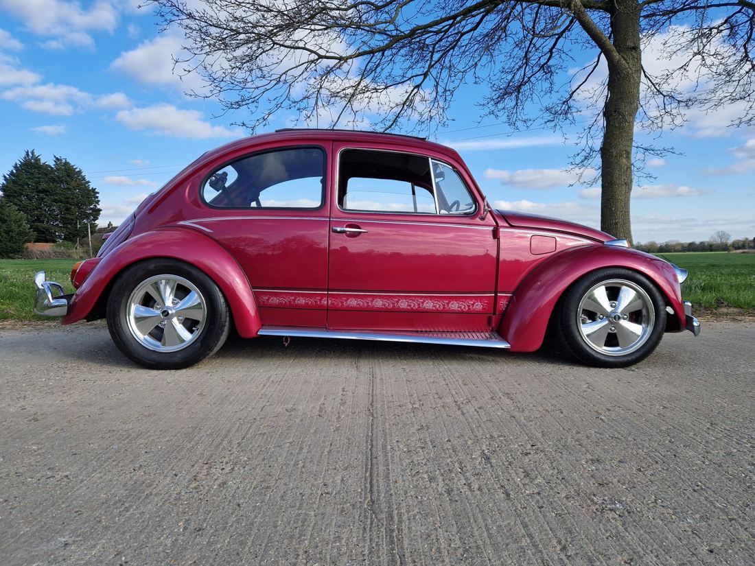 Red custom Beetle beside a field